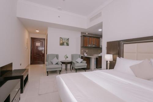 a bedroom with a white bed and a desk and chairs at Alraya Homes by Betu former Times Inn in Abu Dhabi