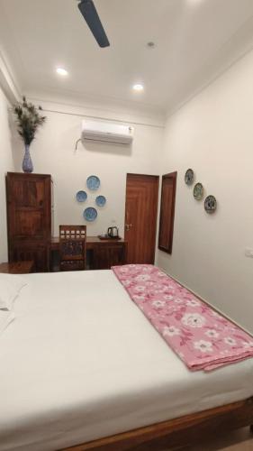 a bedroom with a white bed with a pink blanket on it at Umaid Niwas Homestay in Jaipur