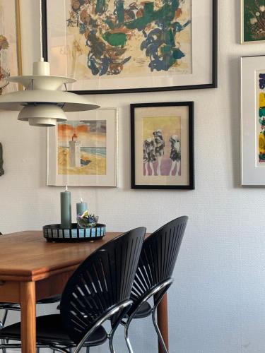 a dining room table with black chairs and pictures on the wall at Det blågrønne Hus in Hals