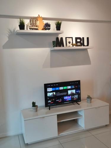 a living room with a tv on a white wall at Summer Suites KLCC by CozyNest in Kuala Lumpur