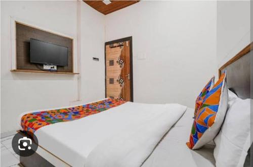 ein weißes Schlafzimmer mit Bett und Flachbildfernseher in der Unterkunft Sunil palace in Parli Vaijnāth