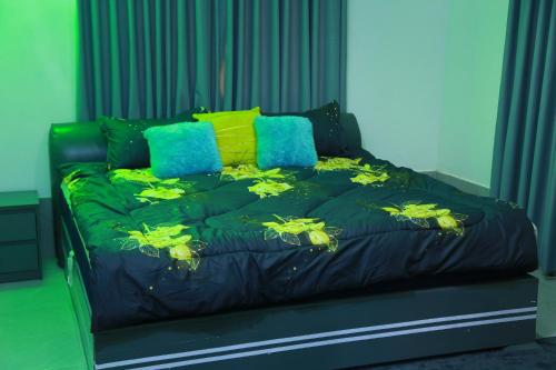 a black bed with yellow and blue pillows on it at Erliz villa in Kumasi
