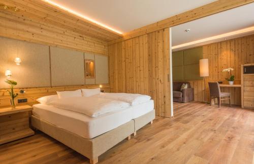 a bedroom with a bed in a room with wooden walls at Hotel Weiher Green Lake in Falzes