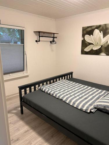 a bed in a room with a flower painting on the wall at Ferienhaus Seeruhe in Flessenow