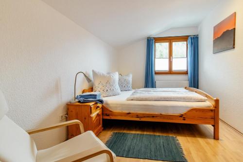 a bedroom with a bed with blue curtains and a window at Ferienwohnung Alpenpanorama in Oberau
