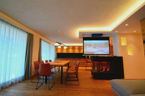 una sala da pranzo con tavolo, TV e camino di BRENTA ALTA ALPINE LODGE MhD a Madonna di Campiglio