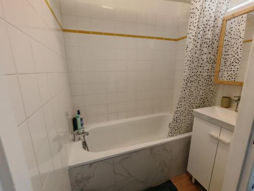 a white bathroom with a tub and a sink at Maison de ville le 101 - 3 chambres - garage in Angoulême