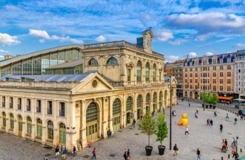 un grand bâtiment avec des gens qui marchent devant dans l'établissement APPARTEMENT BON PLAN 4 personnes - GARE LILLE FLANDRES, à Lille
