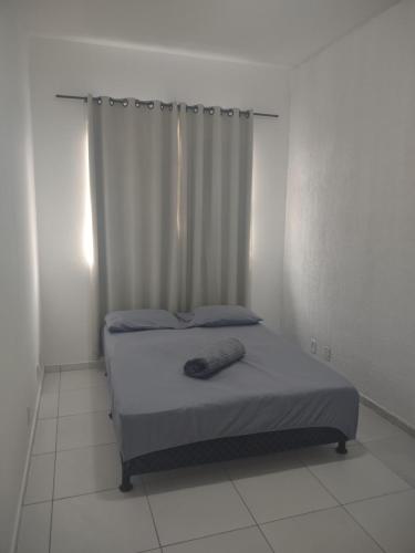 a bed in a white room with a curtain at Casa com 03 Quartos, Piscina e Churrasqueira em Itaipuaçu Maricá RJ in Maricá