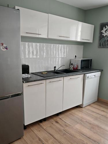 a kitchen with white cabinets and a black counter top at Maison de ville le 101 - 3 chambres - garage in Angoulême