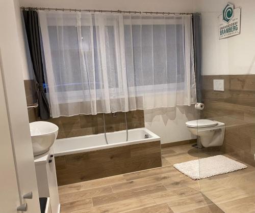 a bathroom with a tub and a toilet and a sink at Smaragdherz in Bramberg am Wildkogel