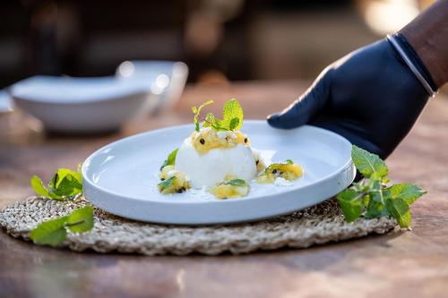 a plate of food with a hand wearing a glove at Karongwe - Kuname Safari Lodge in Hoedspruit