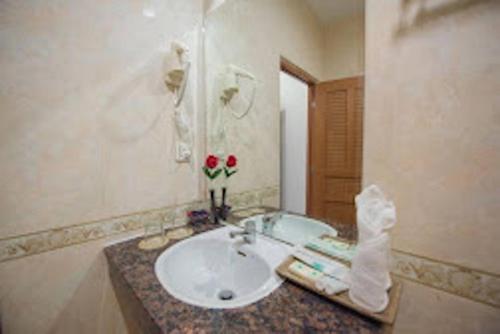 a bathroom with a sink with flowers on a counter at Milan Hotel & Restaurant in Phnom Penh