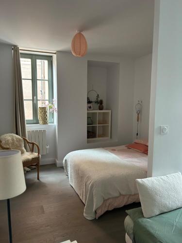 a white bedroom with a bed and a window at Joli petit appartement plein centre in Chalon-sur-Saône
