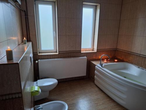 a bathroom with a tub and a toilet and a sink at Szmer Olzy Apartament in Istebna