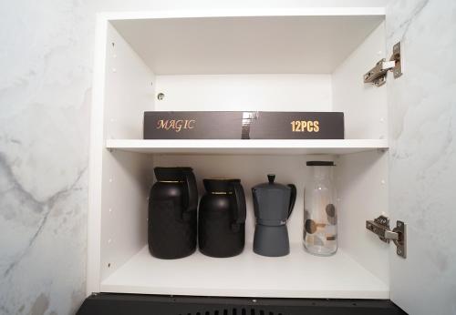 a cupboard filled with black items in a kitchen at 5 min drive from Train Station with Parking, Air Conditioning & IPTV -Ideal for CAN 2025 in Kenitra