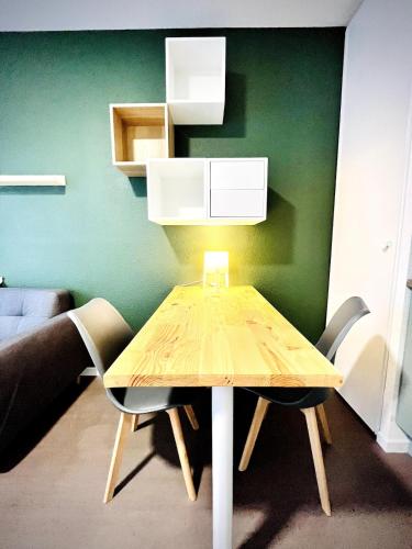 a wooden table with two chairs and a green wall at Ho Toulouse -Joli studio avec balcon in La Celle-sous-Gouzon
