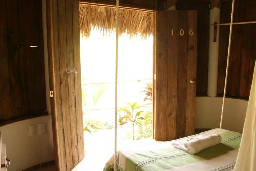a bedroom with a swinging bed with a large window at Cabañas Biuzaa in Zipolite