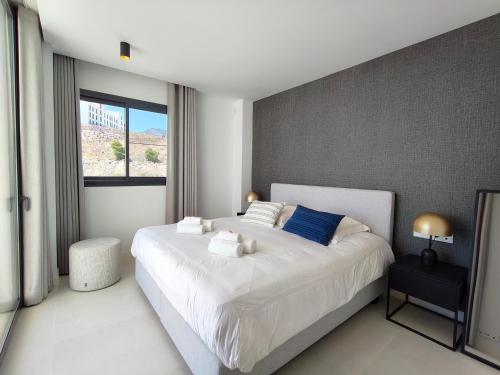 a bedroom with a large white bed with blue pillows at Higueron 5821 luxe appartement met zeezicht in Fuengirola