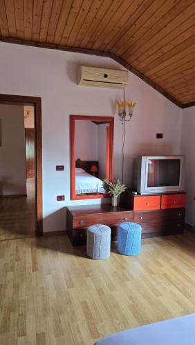 a bedroom with a bed and a television and stools at Eni's Villa, 5km From Shengjini Beach in Lezhë