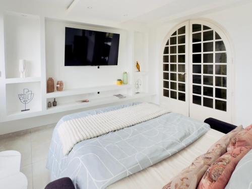 a white bedroom with a large bed and a flat screen tv at Appartement spacieux et lumineux - 10 personnes - entre lacs et montagnes in Fillinges