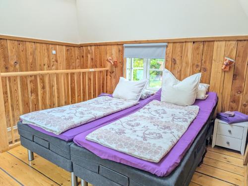two beds in a room with wooden walls at Birkevang The Silo - Rural refuge in Faxe