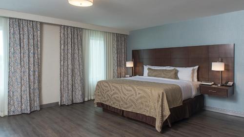 a bedroom with a large bed and two lamps at Staybridge Suites Puebla by IHG in Puebla