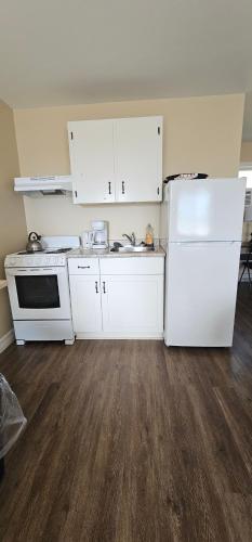a kitchen with white appliances and a white refrigerator at Fair Isle Motel & The Nest in Whycocomagh