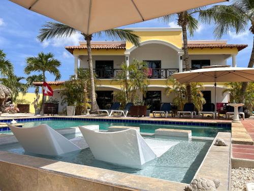 a resort swimming pool with chairs and umbrellas at Sonrisa Boutique Hotel - Adults Only in Kralendijk
