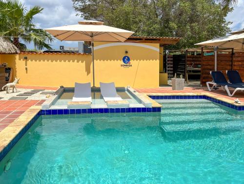 a swimming pool with two chairs and an umbrella at Sonrisa Boutique Hotel - Adults Only in Kralendijk