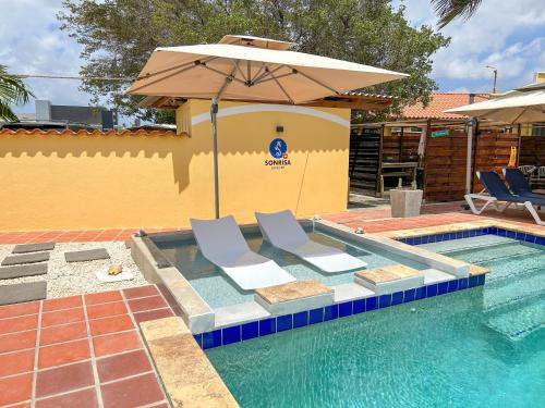 a swimming pool with two chairs and an umbrella at Sonrisa Boutique Hotel - Adults Only in Kralendijk