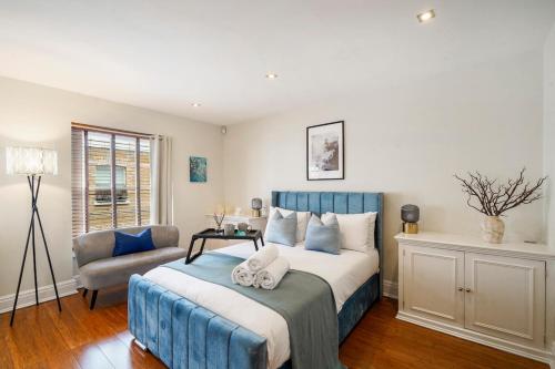 ロンドンにあるElegant 3BR Mews House with Parking in Westminsterのベッドルーム(青いベッド1台、椅子付)