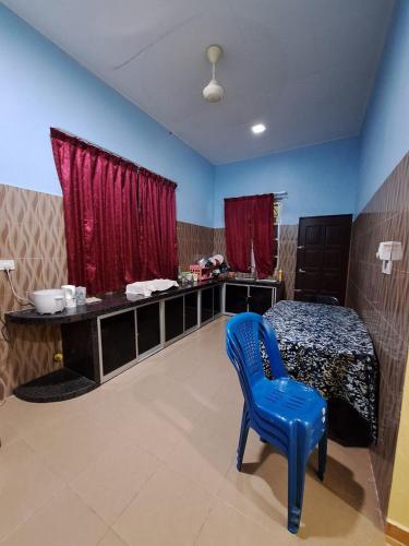 a blue chair in a room with a bed at DTM Homestay 2 in Tanah Merah