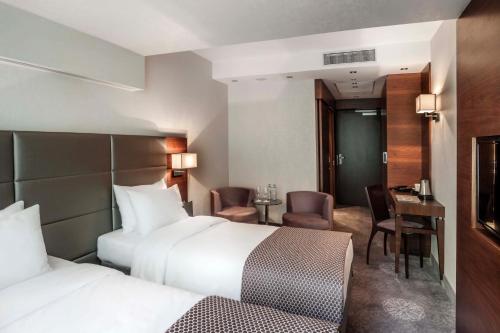 a hotel room with two beds and a desk at Hotel Warszawianka in Jachranka