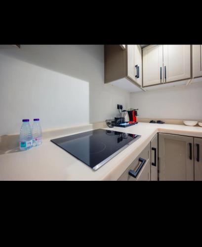 a kitchen with white cabinets and a black counter top at Zad Marina Hotel in Kuwait