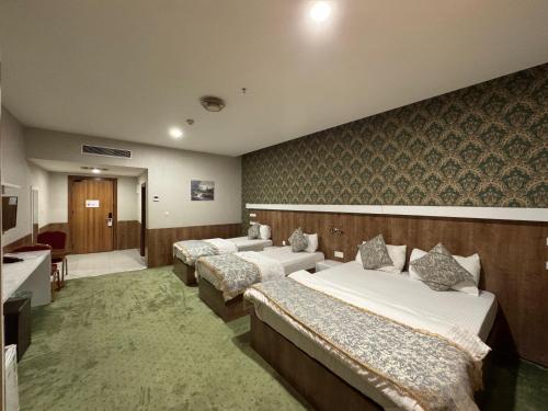 a hotel room with three beds and a bathroom at Al Jawahiri Hotel in Erbil