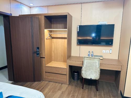 a room with a desk with a television and a chair at Nanjing Restaurant & Motel in Kampala