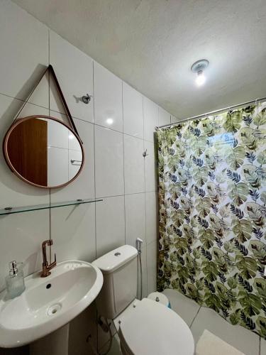 a bathroom with a toilet and a sink and a shower curtain at Suítes Aracuã in Caraíva
