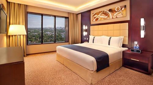 a bedroom with a large bed and a large window at Holiday Inn Cochin by IHG in Cochin