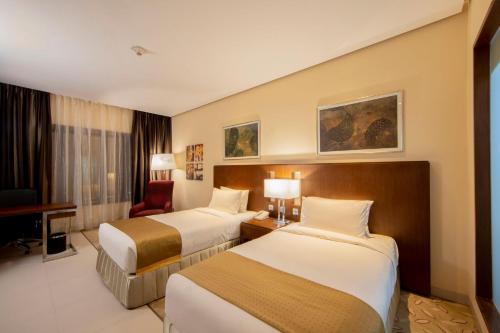 a hotel room with two beds and a desk at Holiday Inn Cochin by IHG in Cochin