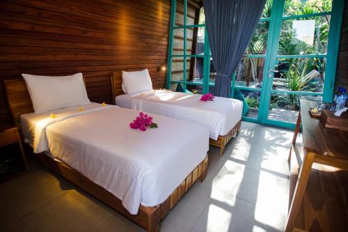 two beds in a room with flowers on them at Waras Villa in Gili Trawangan