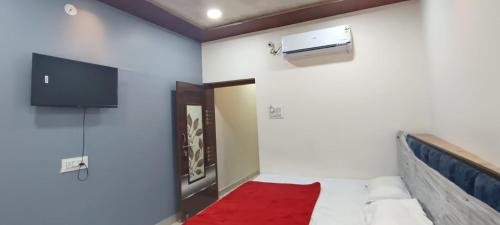 a room with a bed and a tv on the wall at Annapurna Hotel in Ujjain