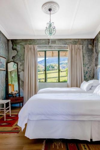a bedroom with a large white bed and a window at Courchevel Cottages in Franschhoek