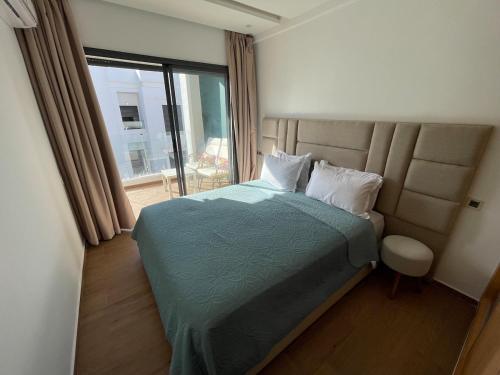 a bedroom with a bed and a large window at Modern Coastal Apartment in Kenitra