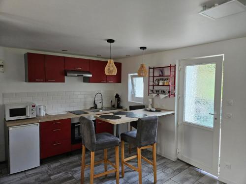 una cucina con mobili rossi, tavolo e sedie di Casă mică și șarmantă la țară a Plonévez-du-Faou