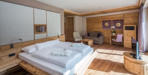 a bedroom with a large bed and a living room at Hotel Weiher Green Lake in Falzes