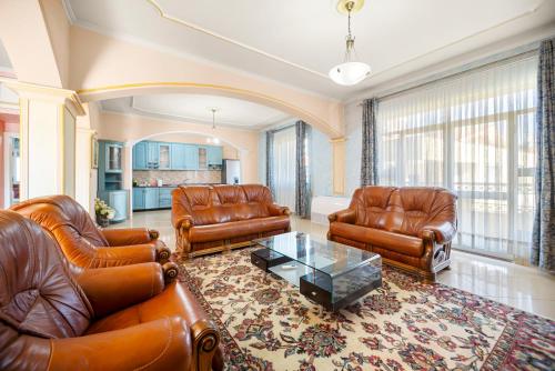 a living room with leather furniture and a table at Vila Rroshaj in Tirana