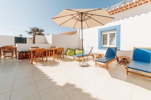 a patio with chairs and tables and an umbrella at AZUL in Zambujeira do Mar
