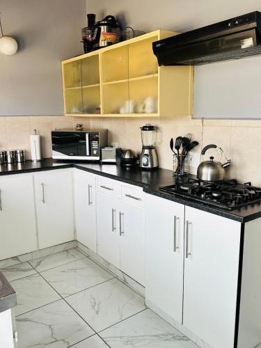 Una cocina con gabinetes blancos y una encimera negra. en Major's Villè, en Swakopmund