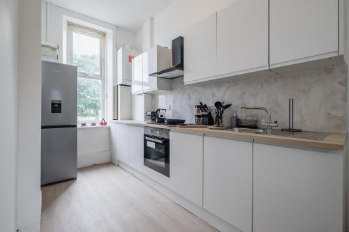 a white kitchen with white cabinets and a sink at Contractors! Free parking, Wifi, 6 BDR, 10 Beds! in Elswick